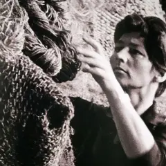 Magdalena Abakanowicz dotyka swojej monumentalnej rzeźby z włókien, tworząc dzieło sztuki.