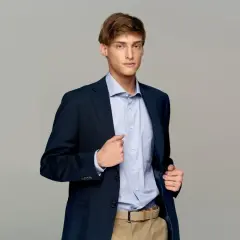 Elegancki mężczyzna w granatowej marynarce i błękitnej koszuli. Idealny przykład, jak ubrać się do klubu mężczyzna, by wyglądać stylowo i pewnie.
